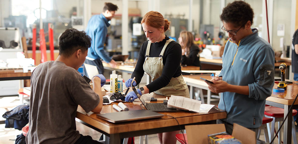 one female and 2 male students working on an engineering project at table